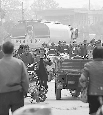 一辆危化品汽油罐车行进在芮城县陌南镇的人流中。